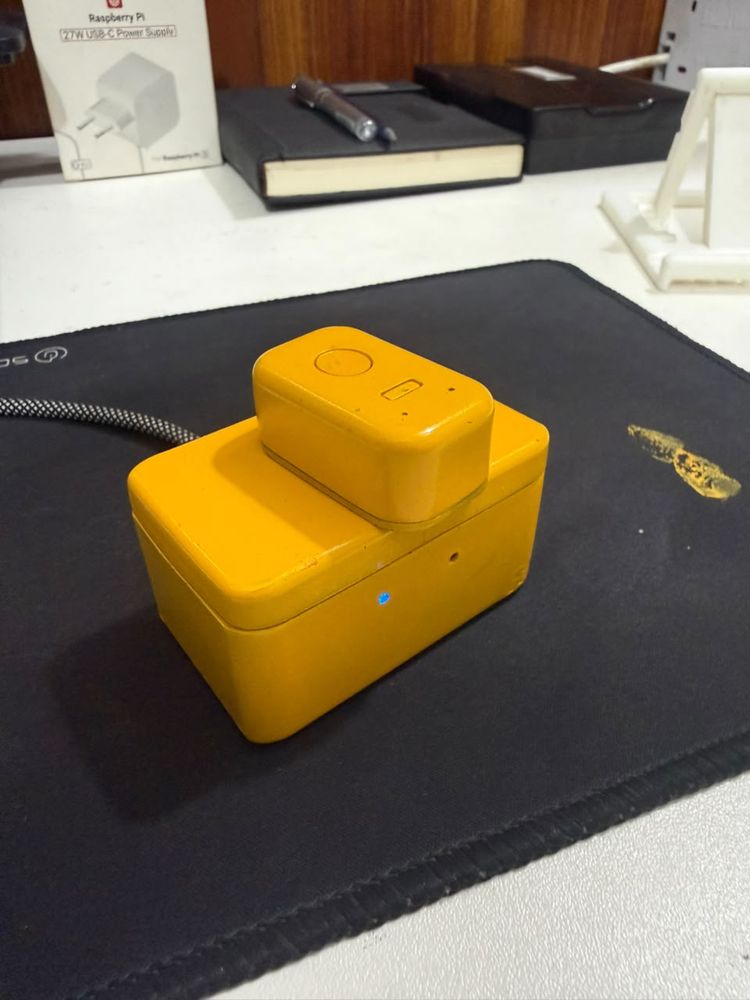 Yellow wearable coaching device docked in its charging pod on the bench, finished product