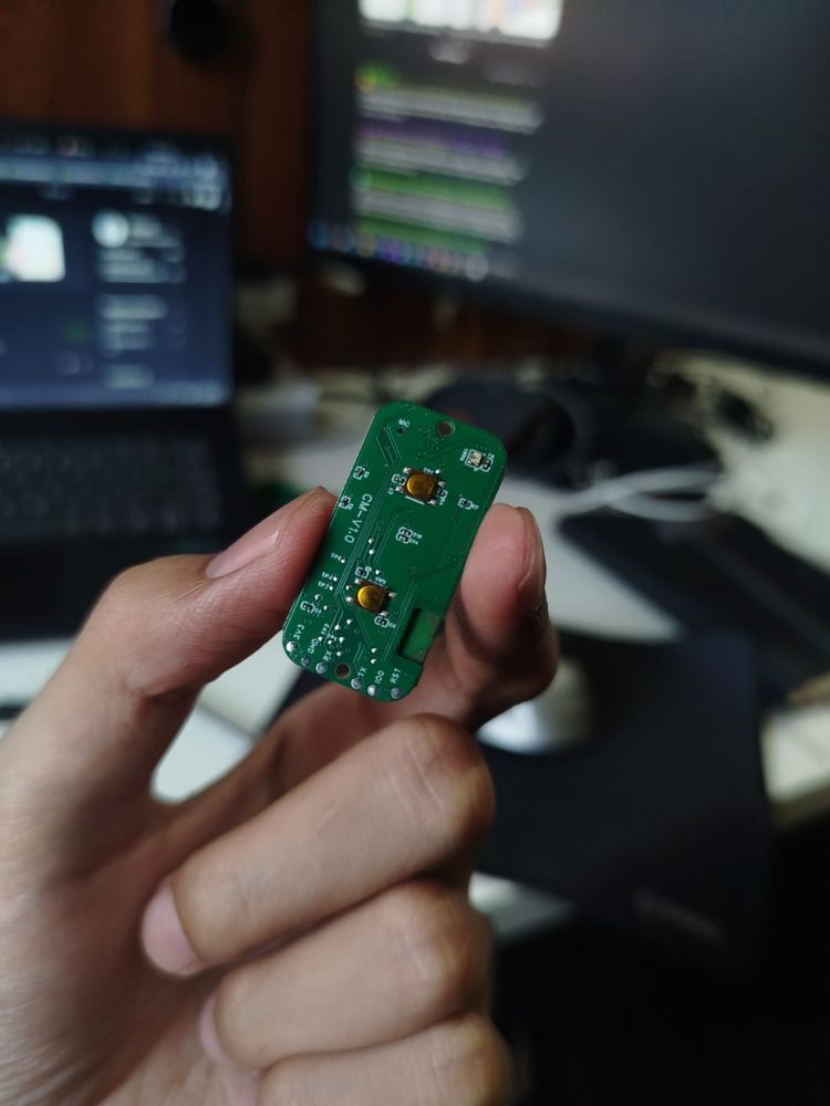 Coaching device main PCB with tactile button, assembled board held in hand