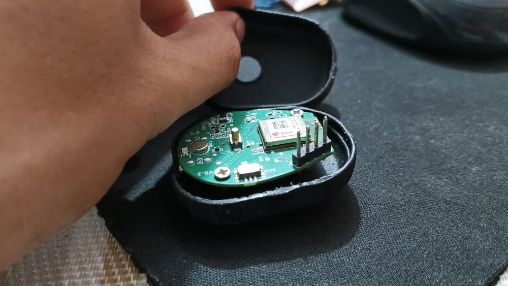 Pebble-shaped enclosure opened to show the round PCB and coin cell seated inside